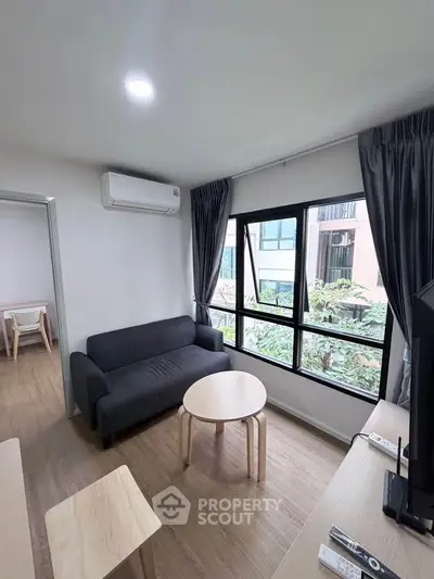 Modern living room with large window and cozy furniture in a stylish apartment.