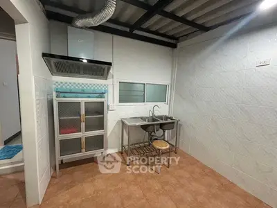Compact kitchen with stainless steel sink and storage cabinet in modern home.