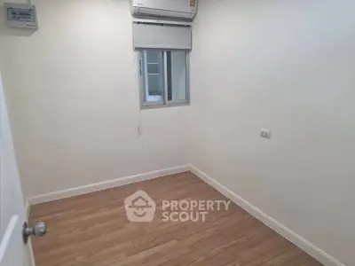 Minimalist small room with wooden flooring and air conditioning unit
