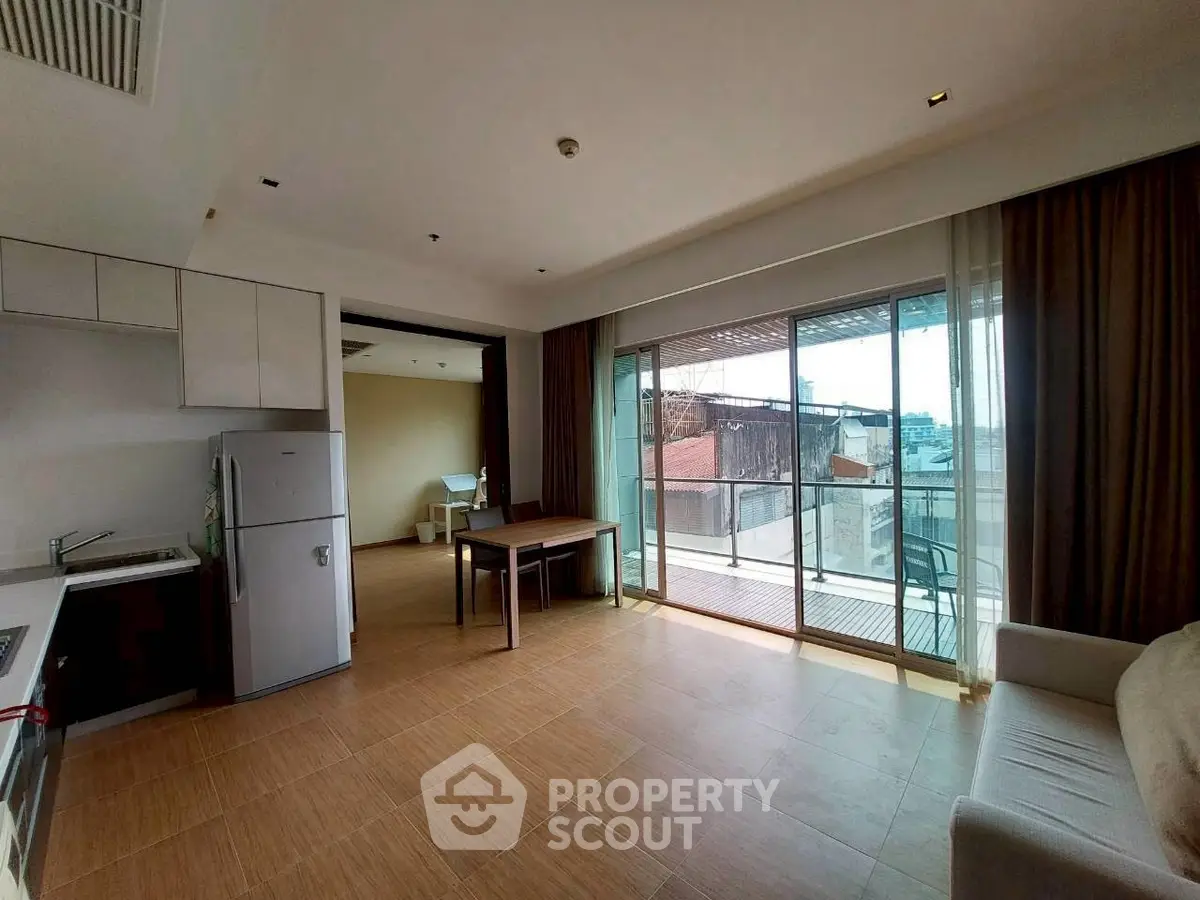 Spacious open-plan living room with balcony and modern kitchen in urban apartment