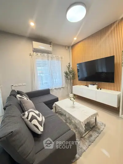 Modern living room with sleek design, featuring a large TV, stylish sofa, and elegant decor.