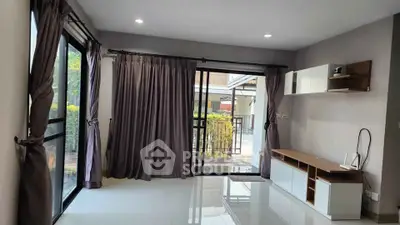 Spacious living room with large windows and modern furnishings, perfect for natural light and comfort.
