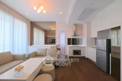 Modern living room with elegant furniture and open kitchen layout, featuring sleek appliances and ample natural light.