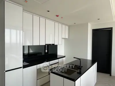 Sleek modern kitchen with high-gloss white cabinetry and contrasting black countertops, featuring state-of-the-art appliances and minimalist design.