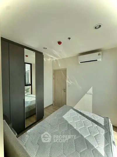 Modern bedroom with sleek wardrobe and air conditioning in a bright apartment.
