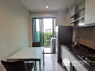 Modern kitchen with sleek black countertops, stainless steel appliances, and ample natural light from the balcony door, perfect for culinary enthusiasts.