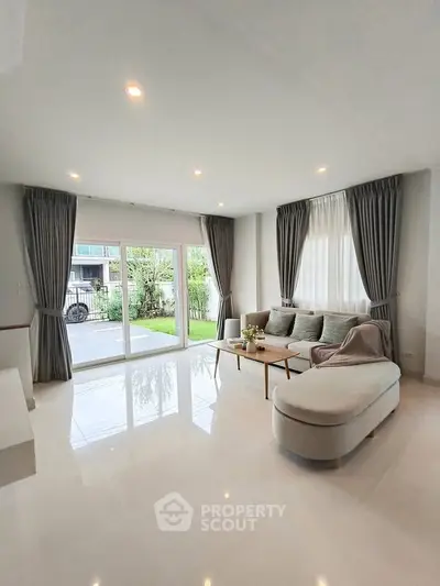 Spacious living room with modern decor and large windows overlooking a garden.