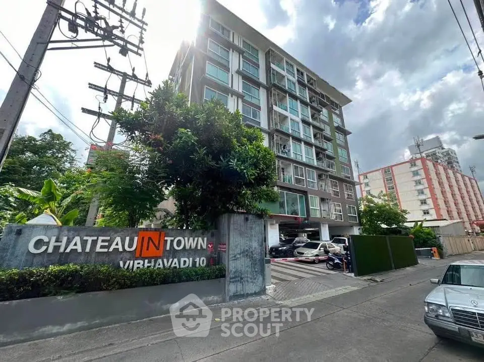 Modern condominium building exterior with lush greenery and urban surroundings.