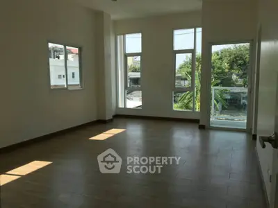 Spacious room with large windows and wooden flooring, offering ample natural light and a serene view.