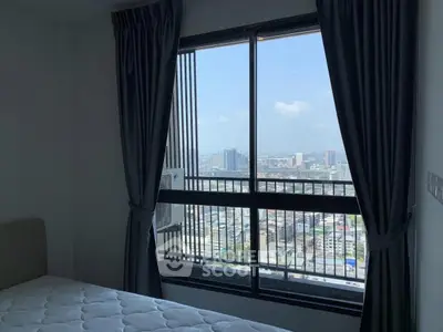 Spacious bedroom with large window offering stunning city view, perfect for urban living.