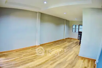 Spacious empty room with wooden flooring and recessed lighting