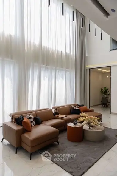 Luxurious living room with high ceilings, elegant curtains, and modern furniture in a spacious setting.