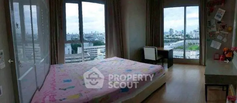 Spacious bedroom with large windows offering stunning city views, perfect for urban living.