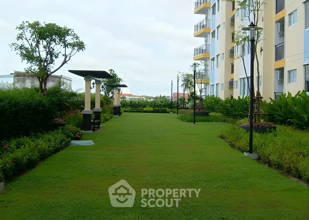 Lush green garden area beside modern apartment building with well-maintained landscaping.