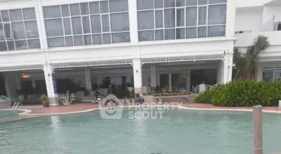 Luxurious poolside view of modern building with lush greenery and spacious outdoor area.
