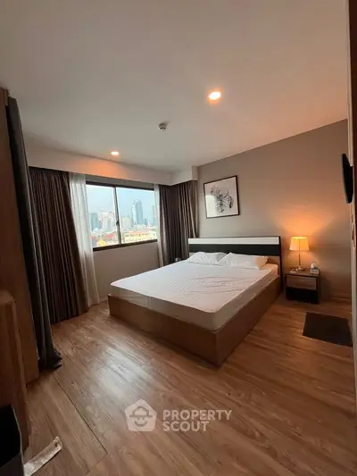 Spacious bedroom with city view and modern decor in a high-rise apartment.