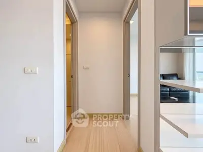 Modern apartment hallway with wooden flooring and open living room view.