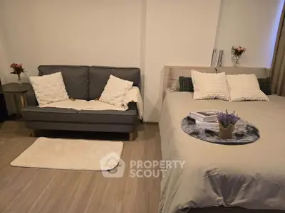 Cozy studio apartment with modern decor, featuring a comfortable bed and stylish sofa, perfect for urban living.