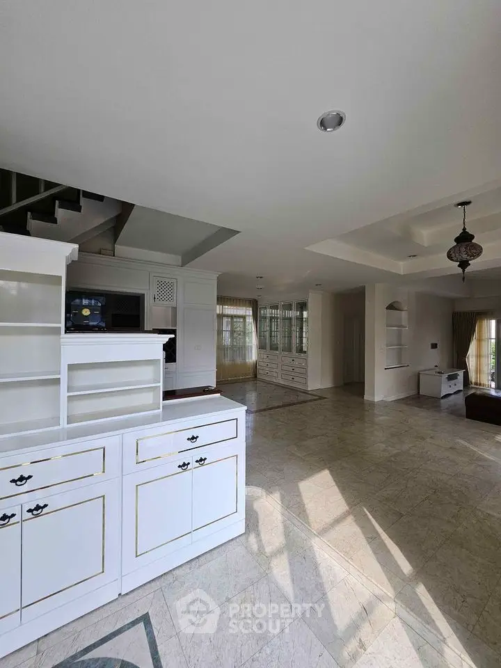 Spacious open-layout living area with elegant white cabinetry and marble flooring