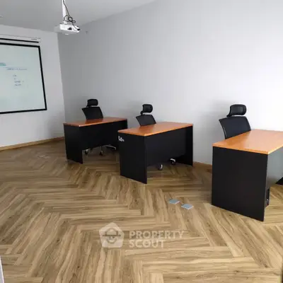 Modern office space with sleek desks and chairs on herringbone wood flooring.