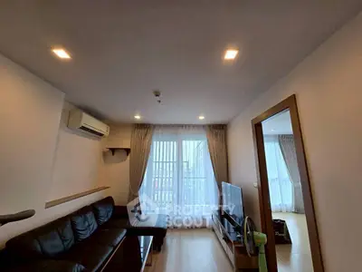 Modern living room with sleek design, featuring a black leather sofa, wooden flooring, and large windows with sheer curtains.