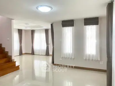 Spacious and bright living room with elegant curtains and staircase