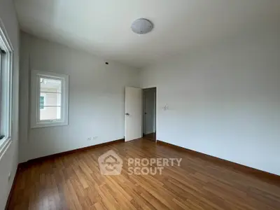 Spacious empty room with wooden flooring and natural light, ideal for customization.