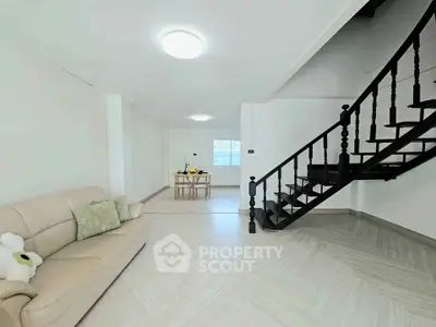 Spacious modern living room with elegant staircase and cozy seating area.