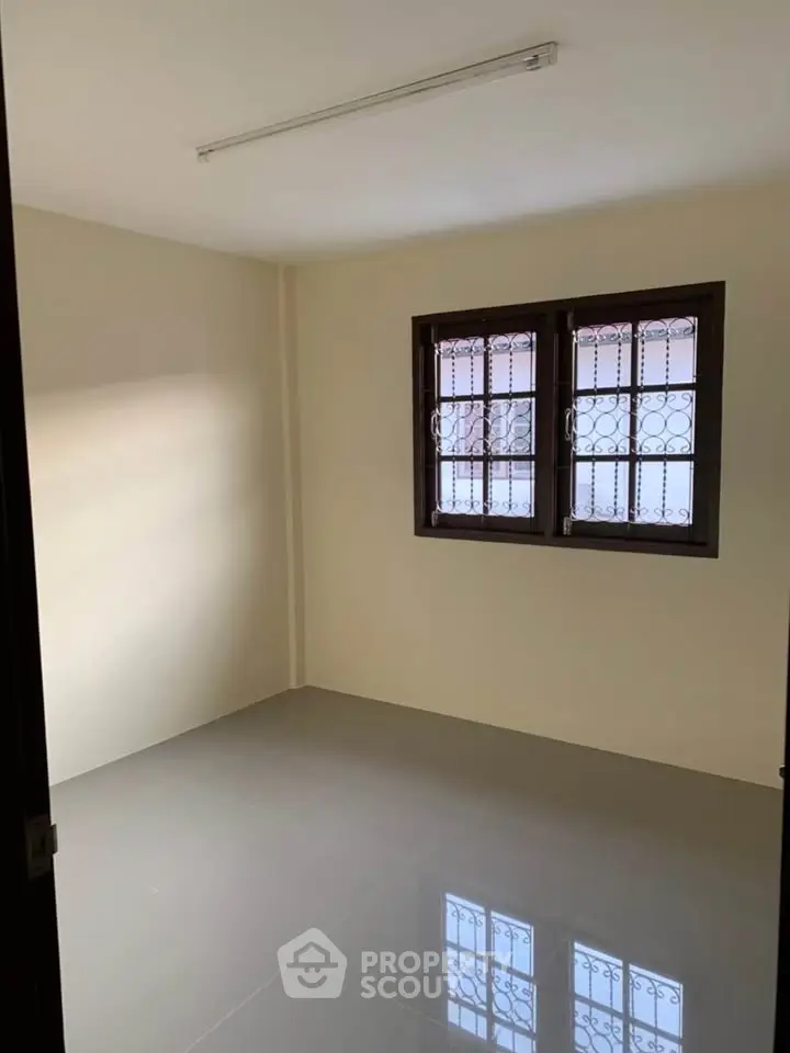 Spacious empty room with large window and tiled floor, perfect for customization.