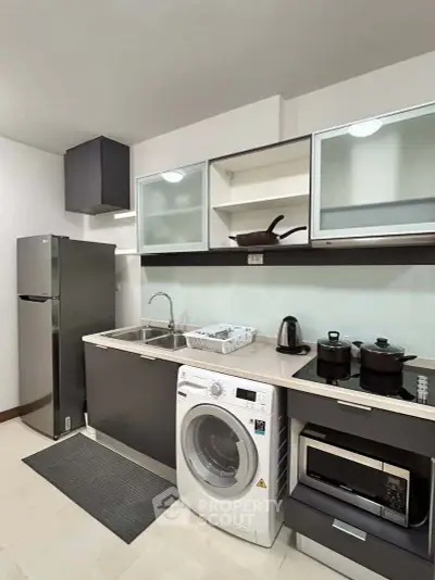 Modern kitchen with sleek appliances including washing machine and microwave, perfect for urban living.