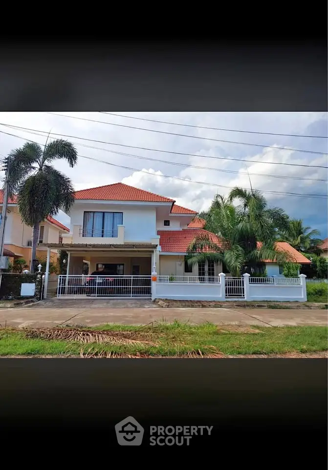 Charming two-story house with red roof and lush palm trees