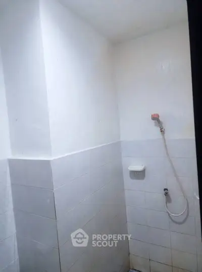 Minimalist bathroom with white tiles and wall-mounted showerhead