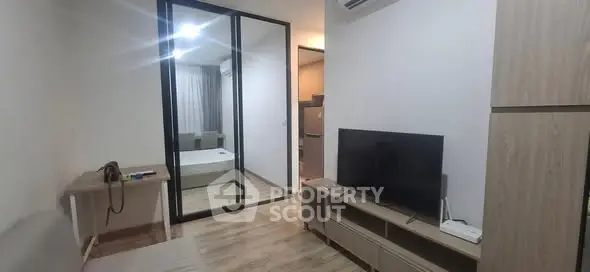 Modern apartment interior with open living area and bedroom, featuring sleek furniture and wooden flooring.
