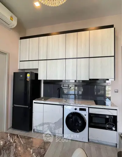 Modern kitchen with sleek cabinetry, marble countertops, and built-in appliances including washing machine and microwave.