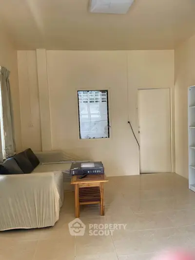 Cozy living room with neutral tones and natural light, featuring a comfortable sofa and a small wooden table.