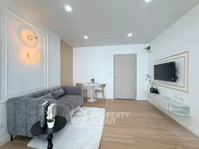 Modern living room with stylish decor, cozy gray sofa, wall-mounted TV, and elegant lighting.