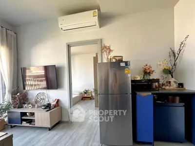 Modern living room with air conditioning and stylish decor, featuring a sleek fridge and open layout.
