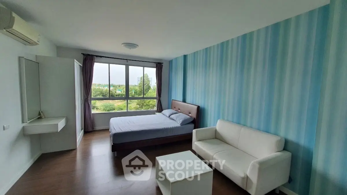 Spacious bedroom with large window and modern furnishings