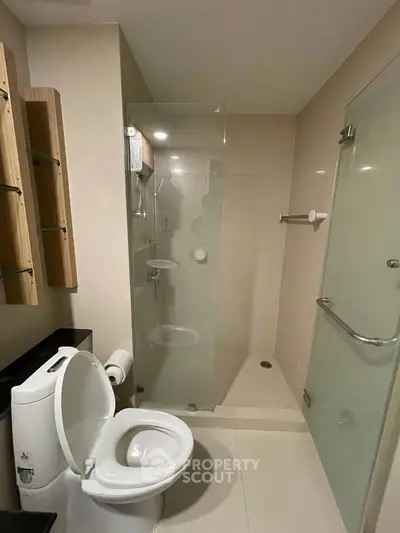Modern bathroom with glass shower and sleek fixtures in contemporary apartment.