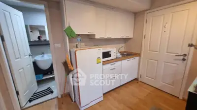 Compact kitchen with white cabinets and appliances in modern apartment