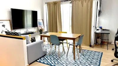 Modern living room with stylish decor, large TV, and natural light.