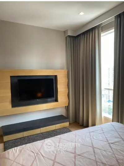 Modern bedroom with large window and built-in TV, offering a cozy and stylish living space.