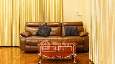Elegant living room with leather sofa and wooden coffee table, featuring luxurious curtains.