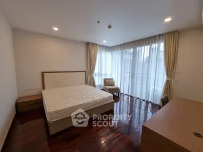 Spacious bedroom with large windows and wooden flooring in modern apartment
