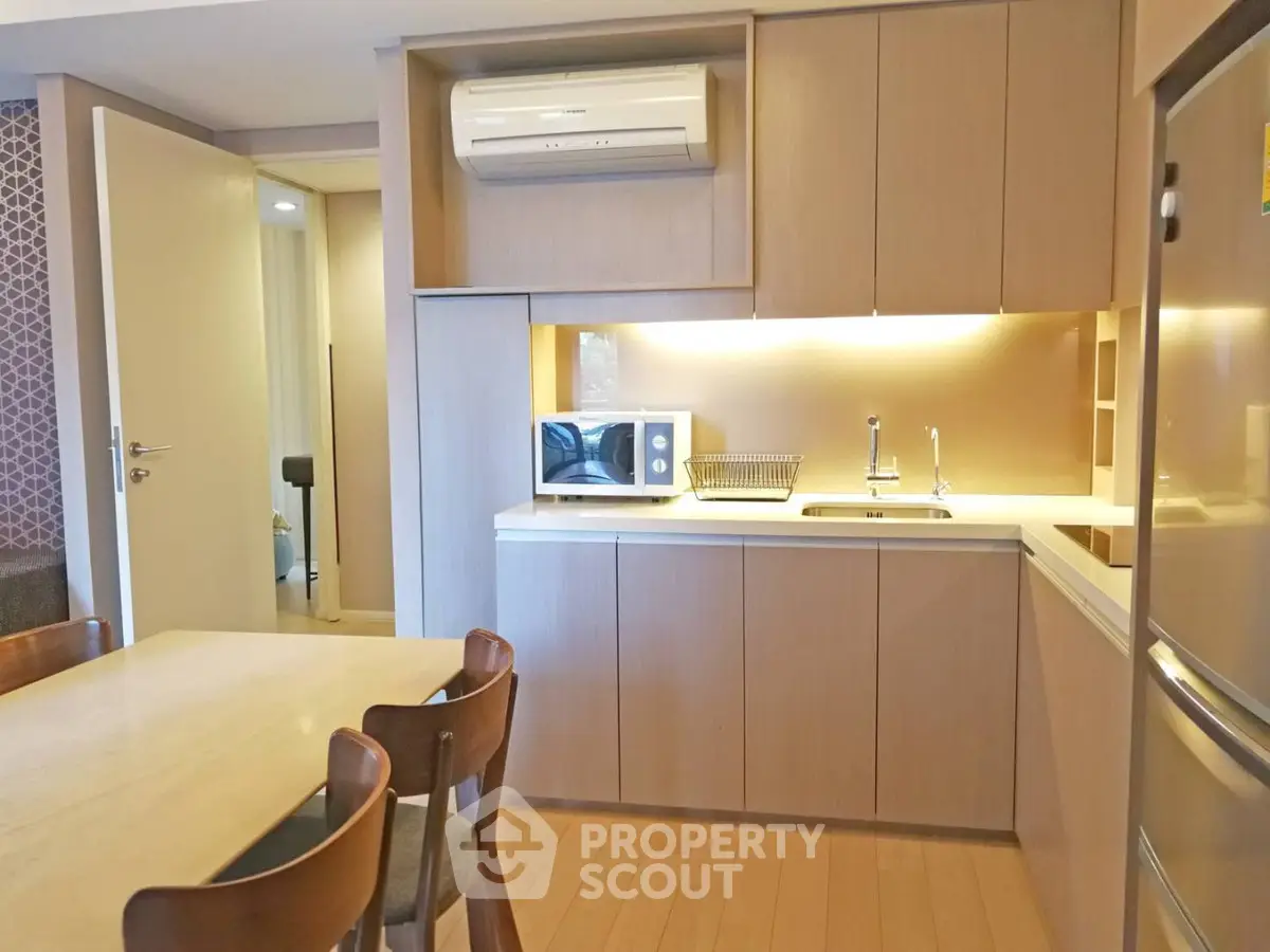 Modern kitchen with wooden cabinets and dining area in cozy apartment