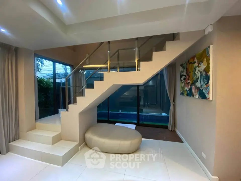 Modern interior with stylish staircase and large windows overlooking a pool, perfect for luxury living.