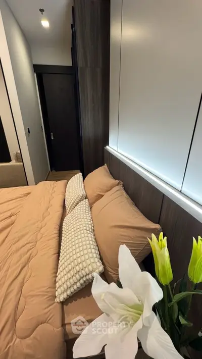 Cozy bedroom with modern decor and elegant lighting, featuring plush bedding and stylish floral accents.