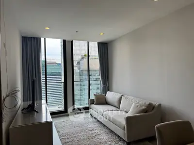 Modern living room with city view, featuring sleek sofa and large windows.