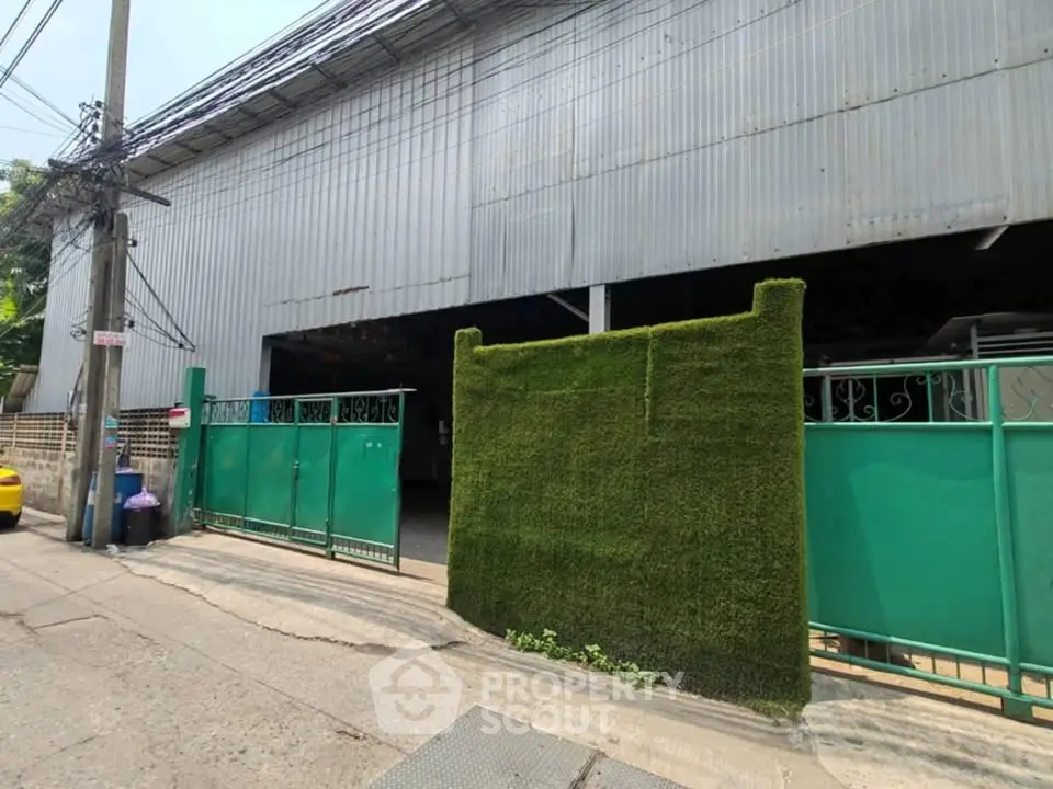 Spacious industrial warehouse with secure green gates and ample outdoor space.