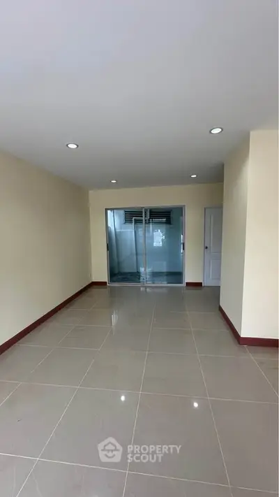 Spacious empty room with glossy tiled floor and sliding glass doors